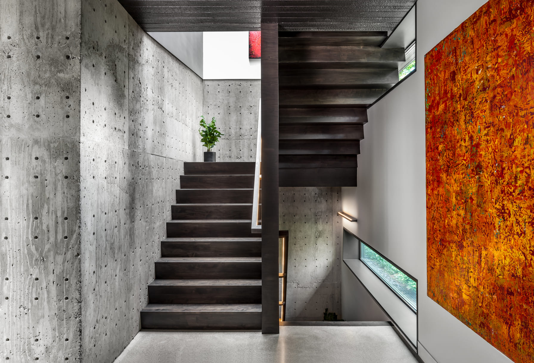 Stunning interior design and architecture featuring a modern staircase, concrete, and feature wall.