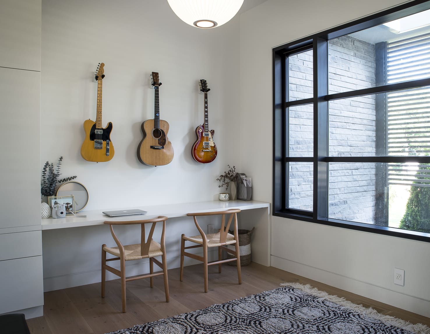 Three guitars strung on the wall beside a stunning window view.
